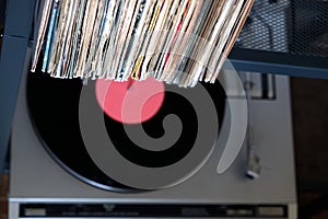 Stack of many vinyl records in old covers and turntable in gray case