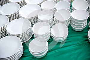 stack of many white plates on the table to prepare for catering buffet. tableware for lunch and dinner