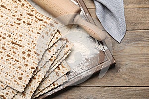 Stack of matzos and rolling pin on wooden table, flat lay