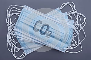 A stack of medical blue masks with a carbon dioxide formula on a gray background