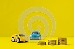 Stack of money and cars toy on yellow background, concept of buy a car