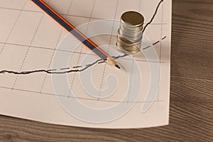 Stack of money coins with graph paper and pencil