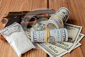 Stack of Money, drugsand a gun on a wooden table, concept about danger and threat of the drug