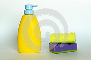 Stack of multi-colored dish wash sponges with bottle of soap. Household cleaning scrub pad. Home cleaning concept.