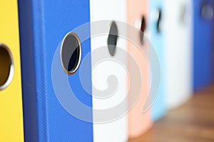 Stack of multi-colored folders is on the table.