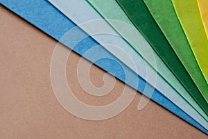 a stack of multi colored tissue paper spread out in a fan on a background of brown cardboard