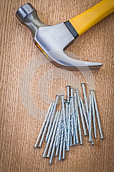 Stack of nails and claw hammer on wooden board