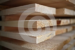 Stack of natural rough wooden boards close-up. Storage of wood in a carpenter`s workshop or at a sawmill