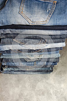 A stack of neatly folded jeans on gray background. Close-up of jeans in different colors. Copy space. Selective focus