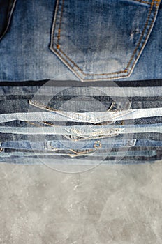 A stack of neatly folded jeans on gray background. Close-up of jeans in different colors. Copy space. Selective focus