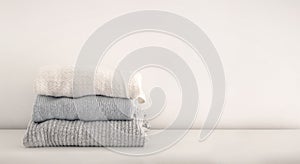 Stack of neatly folded woolen knitwear. Minimal lifestyle, capsule wardrobe. Autumn-winter wardrobe concept. Light and