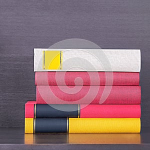 Stack of new colorful books in the wooden bookself.