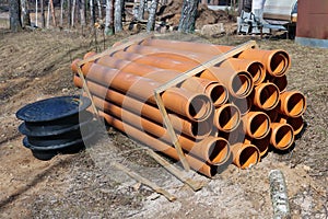 Stack of new plastic drainage pipes at construction site