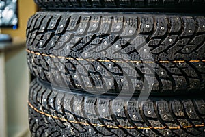 Stack of new winter studded tyre with metal spikes in store, rubber auto car wheels