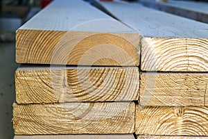 Stack of new wooden studs at the lumber yard. Wood timber construction material. Shallow depth of field effect