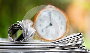 Stack of newspapers with alarm clock, daily news background