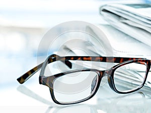 Stack of newspapers and eyeglasses on background