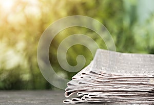Stack of newspapers on table against blurred green background, space for design. Journalist`s work