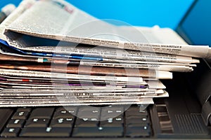 Stack of newspapers on laptop photo