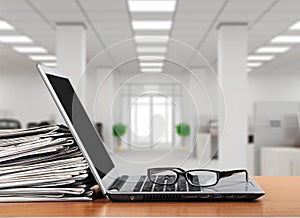 Stack of newspapers with laptop on wooden table