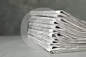 Stack of newspapers on light grey stone table. Journalist`s work