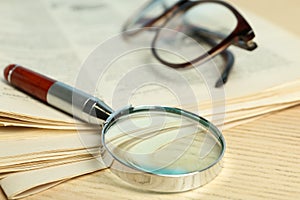 Stack of newspapers, magnifier and glasses on table. Search concept