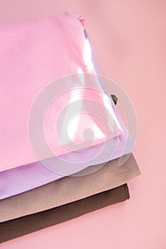 Stack of nude pink clothes on pink background and the rays of the sun