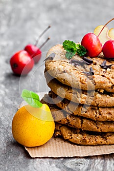 Stack of oat cookies with quince and wild apples on wooden back