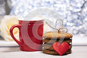 A stack of oatmeal cookies, a heart and a red mug. Tea drinking with loved ones. The photo