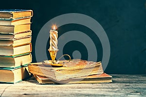 Stack of old antique books and lighten candle