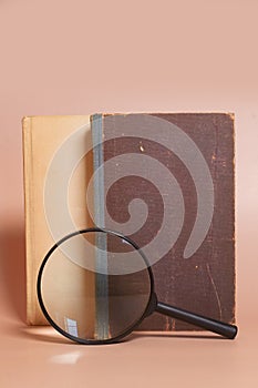 A stack of old battered books and a magnifying glass