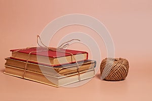 A stack of old battered books tied with jute rope, a coil of jute rope