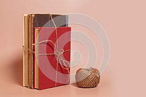 A stack of old battered books tied with jute rope, a coil of jute rope