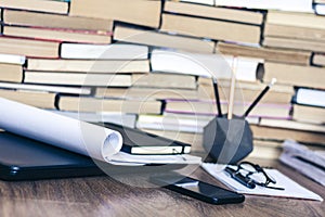 Stack of old book on wooden table, laptop computer, notebook, smartphone, stationery and paperweight. Education writer concept