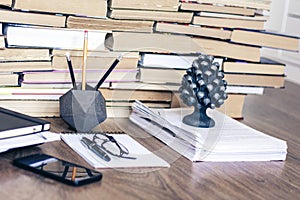 Stack of old book on wooden table, laptop computer, notebook, smartphone, stationery and paperweight. Education writer concept