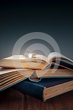A stack of old books with a burning candle and copy space