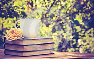 Stack of old books, cup of tea and rose.