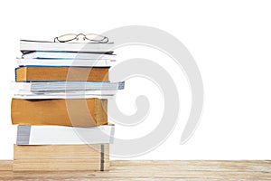 Stack of old books with eyeglasses on wooden table on white background