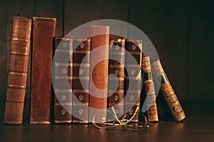 Stack of old books with glasses on desk