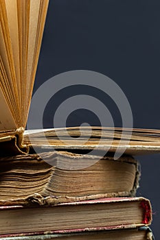 stack of old books with opened one on top on dark background. Old books in the library. Bookshelf shop. Knowledge publications,