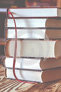 A stack of old books on table against background of bookshelf in library. Conceptual background on education, literature photo