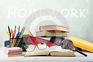 A stack of old color books, glasses, stationery and magnifying glass on a table and text