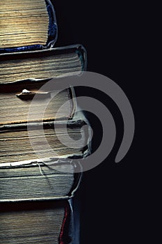 Stack of old dusty shabby books on black background