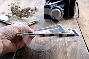 Stack of old family photos, vintage photographs of 50s, 40s, black retro accordion camera on wooden table, concept of genealogy,