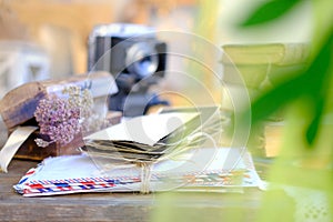 Stack of old family photos, vintage photographs of 50s, 40s, black retro accordion camera on wooden table, concept of genealogy,