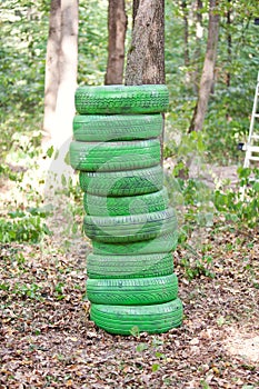 Stack of old green tires in the forest