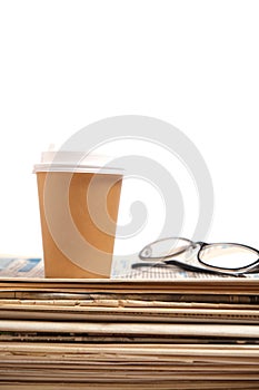 Stack old newspapers, glass of coffee and glasses for reading newspaper news