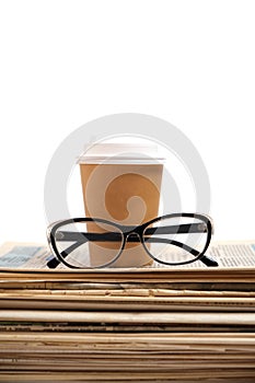 Stack old newspapers, glass of coffee and glasses for reading newspaper news