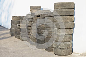 A stack of old tires near a white wall.