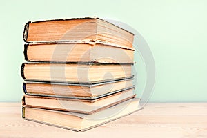 Stack of old used books on wooden table and blue background. Pile of vintage old hardback books. Back to school